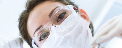 Dentist In Mask Holding Angled Mirror And Drill