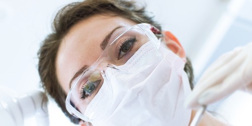 Dentist In Mask Holding Angled Mirror And Drill