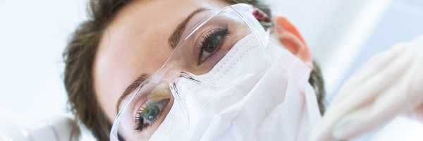 Dentist In Mask Holding Angled Mirror And Drill